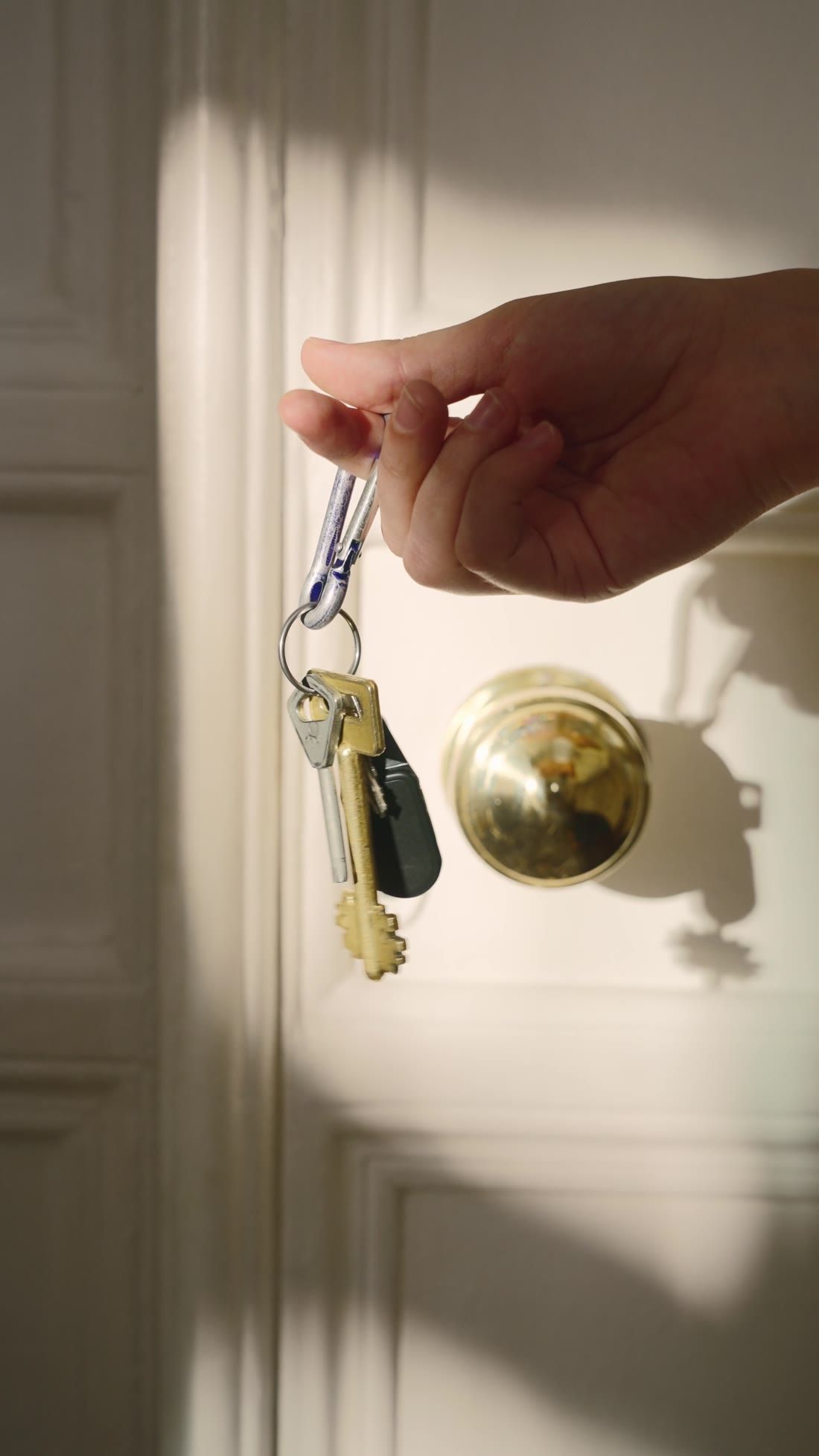 A hand holding a set of keys at a door